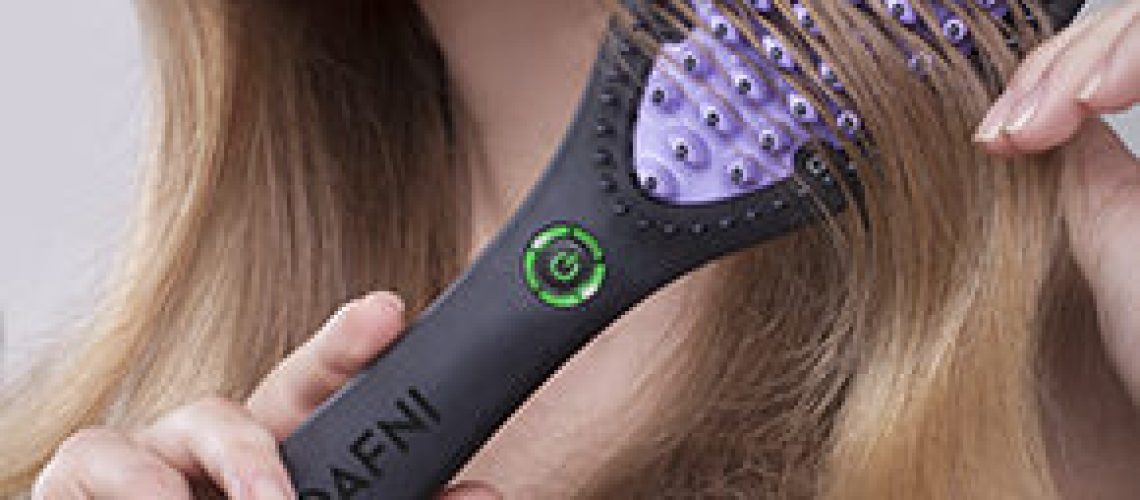 Ceramic straightening brush being drawn through long blonde hair